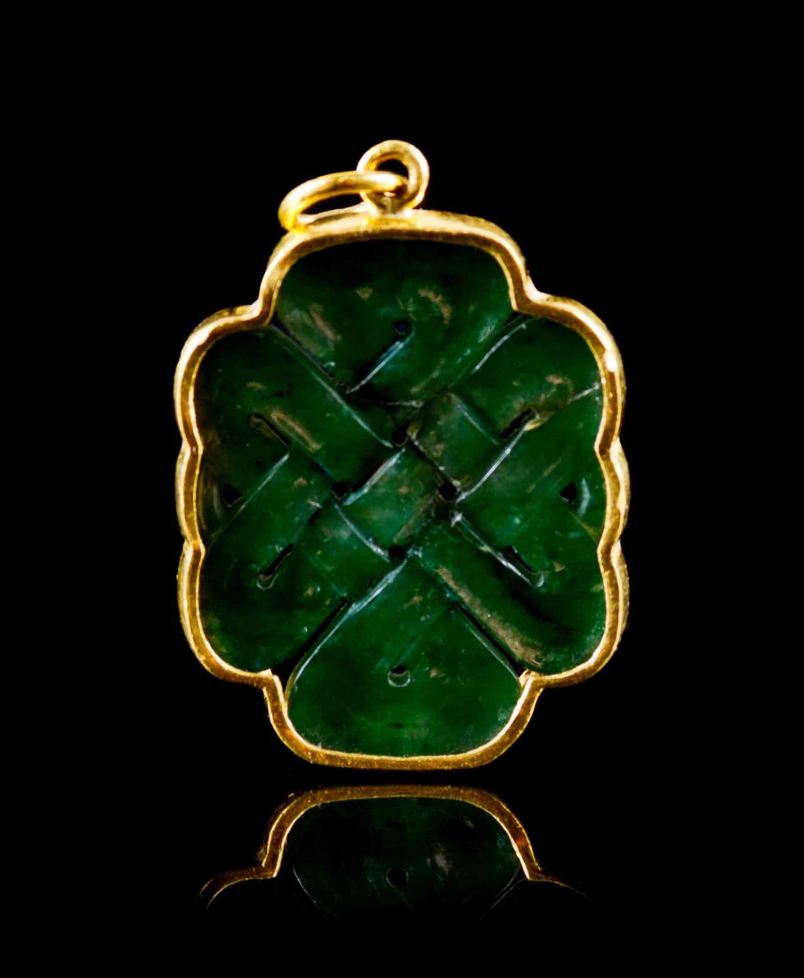 A Spinach Green Jade Pendant, Height 1 3/8 inches.: A Spinach Green Jade Pendant, pierce carved to depict the Buddhist endless knot, mounted in yellow gold. Height 1 3/8 inches. Condition: In overall good condition with natural fissures and inclusions 