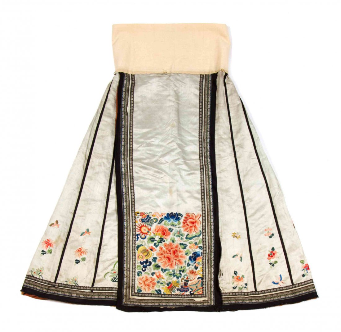 A Chinese Silk Skirt, Height of first 38 3/8 inches.: A Chinese Silk Skirt, of a grey silk and having French knot decoration, depicting peonies and Buddhist emblems, with embroidered lotus and black silk ribbon borders, together with a skirt fragment of 