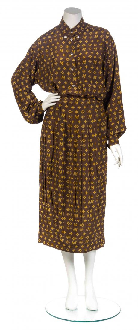 A Moschino Brown LV" Print Skirt Ensemble, Skirt size: A Moschino Brown "LV" Print Skirt Ensemble, comprised of a silk button up blouse, with patch pockets and silvertone cowboy hat buttons, together with a knife pleated skirt. Labeled: Moschino. Skirt si