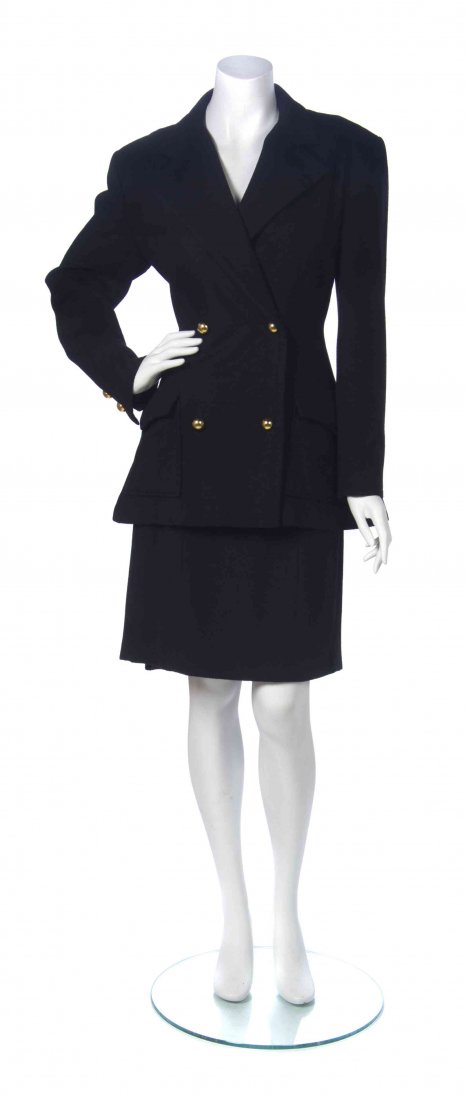 A Patrick Kelly Black Wool Skirt Suit, Size 10.: A Patrick Kelly Black Wool Skirt Suit, comprised of a double breasted jacket with inverted pleats to the back, together with a fitted skirt with an inverted pleated back hem. Labeled: Patrick Kelly. S