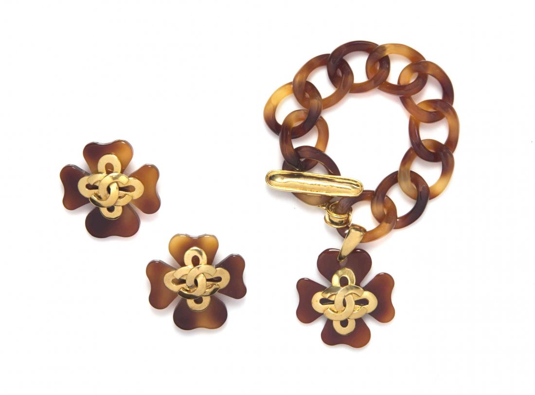 A Chanel Brown Lucite Demi-Parure,: A Chanel Brown Lucite Demi-Parure, comprised of a chain link bracelet with brown Lucite and goldtone camellia charm, and a pair of matching camellia earclips. Stamped: Chanel. Condition: Measurements: