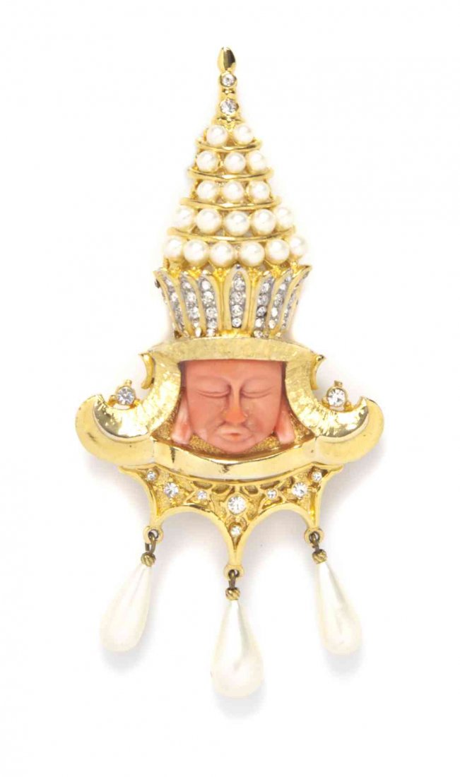 A Hattie Carnegie Coral and Goldtone Asian Deity: A Hattie Carnegie Coral and Goldtone Asian Deity Brooch, with a pave pearl and rhinestone headdress, and three dangling tear drop pearls. Stamped: Hattie Carnegie. Property from a Private Collection C