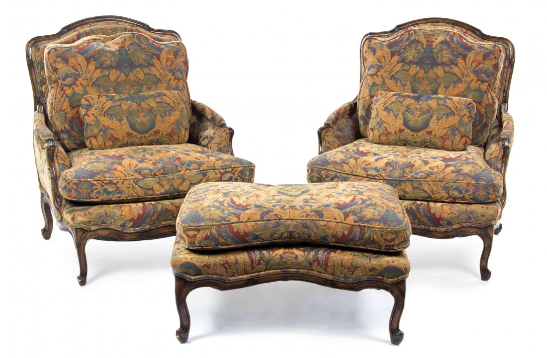 A Pair of Louis XV Style Walnut Bergeres, Height of cha: A Pair of Louis XV Style Walnut Bergeres, each having a padded back into downswept arms over a cushion seat, raised on cabriole legs ending in scroll feet, with an associated footstool. Height of chai