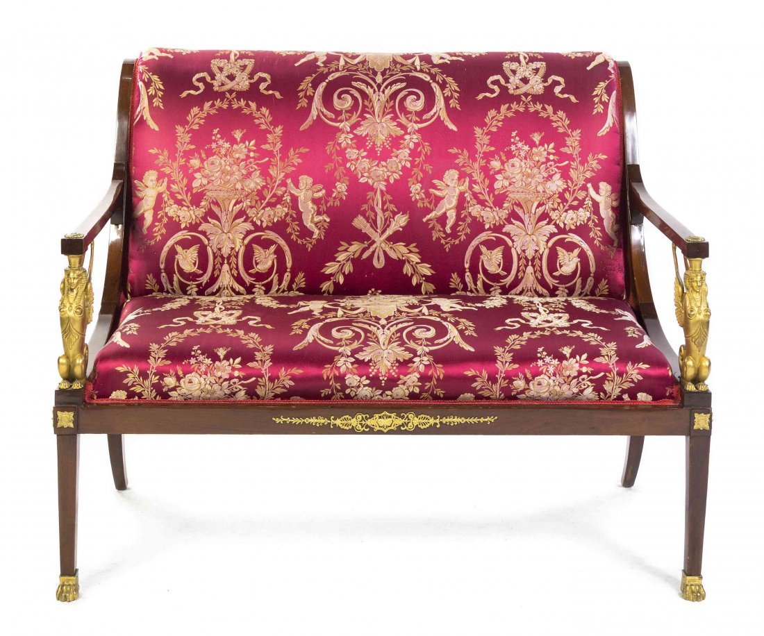 A French Empire Style Gilt Bronze Mounted Mahogany: A French Empire Style Gilt Bronze Mounted Mahogany Settee, having an everted crest over the upholstered back and seat within open arms supported by winged sphinxes, raised on square tapering legs endi