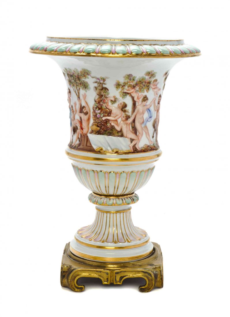 A Meissen Gilt Bronze Mounted Porcelain Vase, Height: A Meissen Gilt Bronze Mounted Porcelain Vase, of urn form, decorated in the Capodimonte style with a continous band of Bacchic figures, urn and base each with crossed swords in underglaze blue and inc