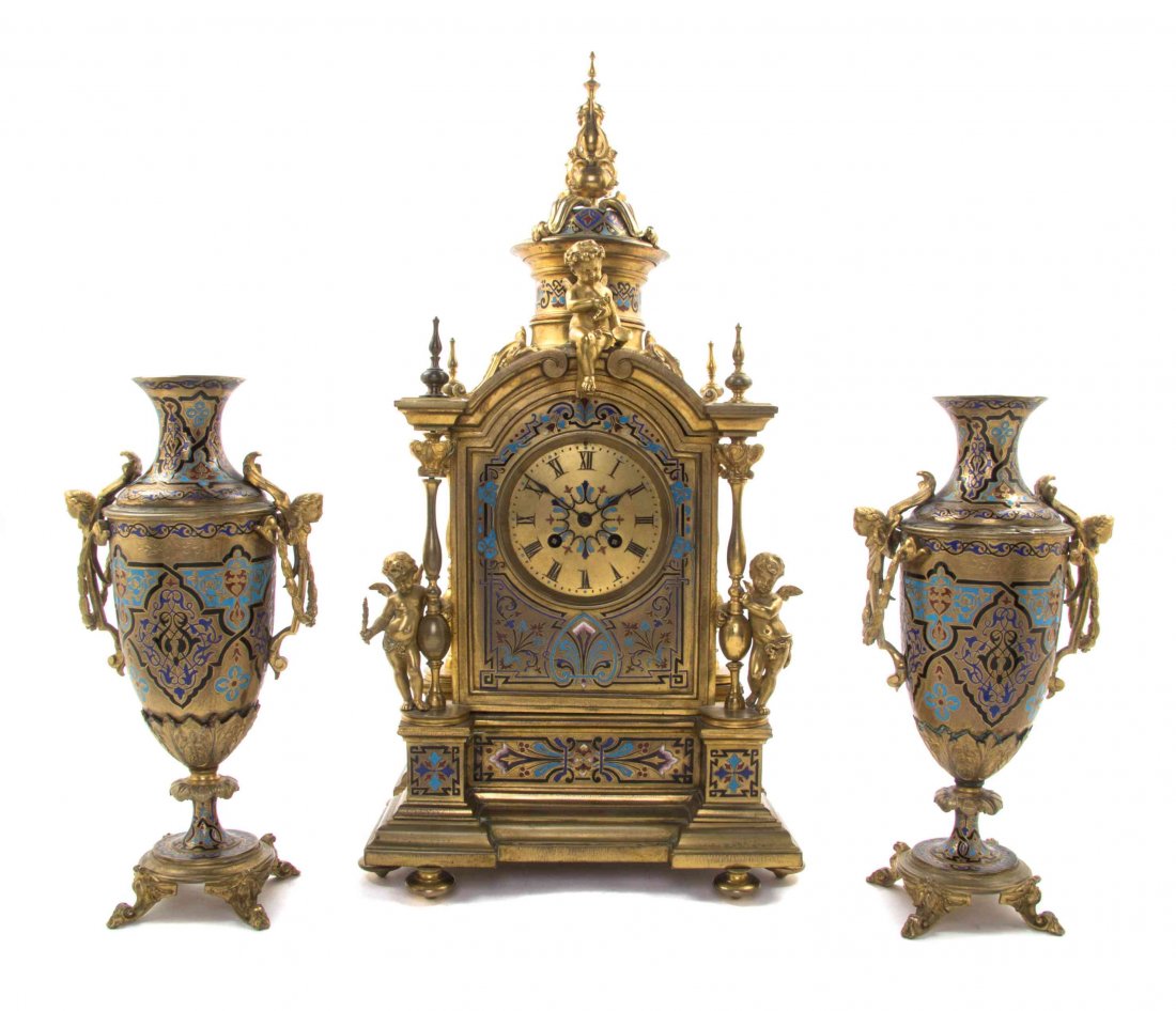 A Continental Gilt Bronze and Champleve Clock: A Continental Gilt Bronze and Champleve Clock Garniture, 19TH/20TH CENTURY, MOVEMENT BY JAPY FRERES, the clock of architectual form having a circular dial with Roman numerals and cast with three cheru