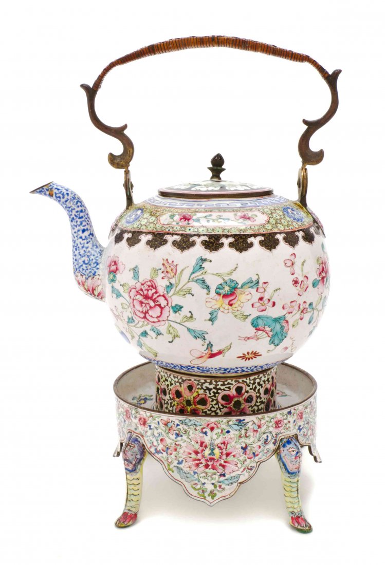A Canton Enamel Teapot on Warming Stand, Height over: A Canton Enamel Teapot on Warming Stand, the teapot with a caned swing handle and enameled to show flowers on a white ground, the warming stand with four legs headed by lions and ending in paw feet. H
