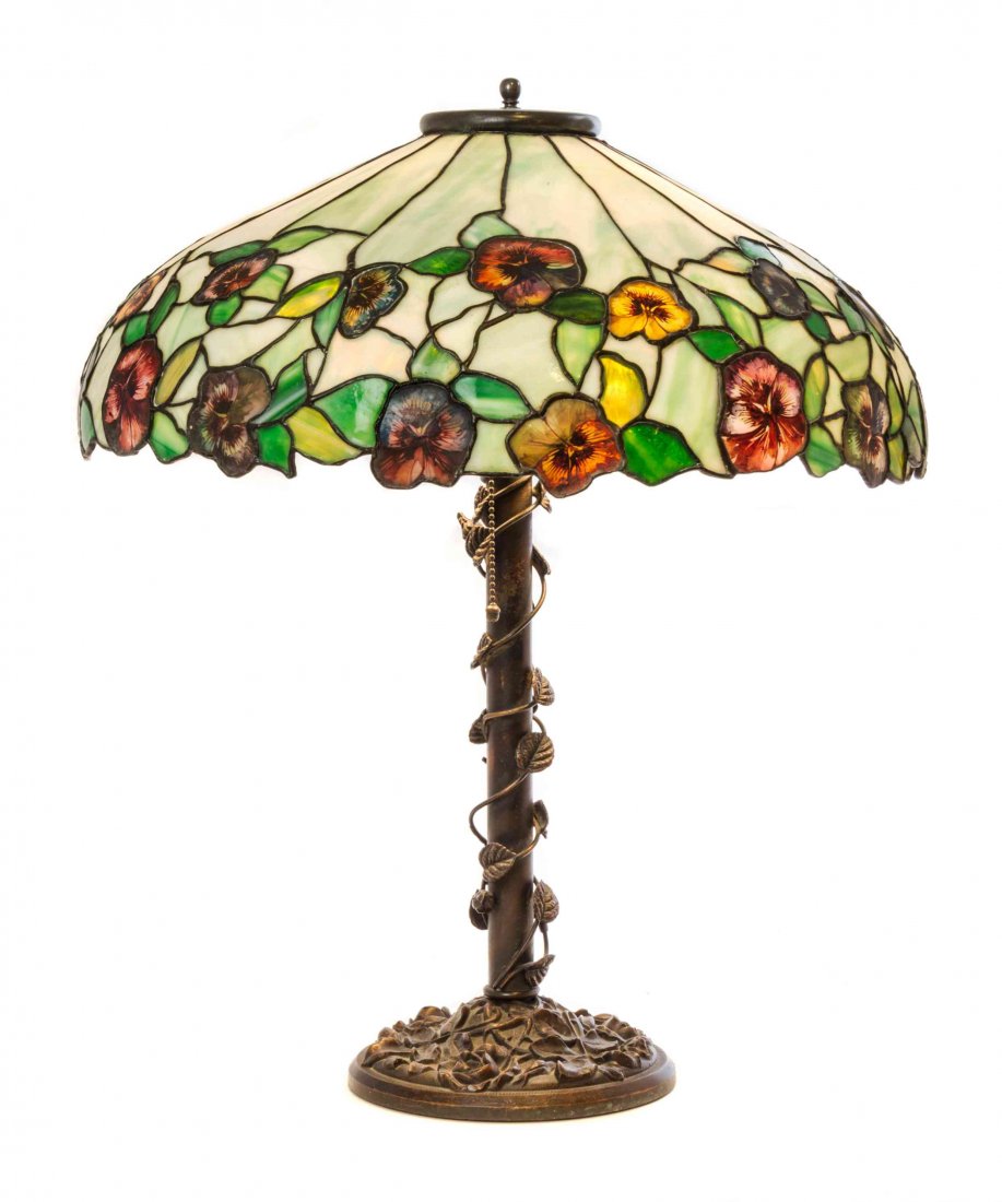 A John Morgan and Sons Leaded Glass Table Lamp, Height: A John Morgan and Sons Leaded Glass Table Lamp, in the Pansy pattern, the shade of domed form, the lower border with pansy decoration, the bronze base of tapering form with vine and rose decoration. H
