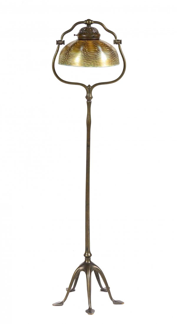 A Tiffany Studios Gold Favrile Glass and Bronze Floor: A Tiffany Studios Gold Favrile Glass and Bronze Floor Lamp, the damascene shade of dome dimpled form, with pulled decoration, set on a harp base over a tubular standard, raised on five spade feet, the