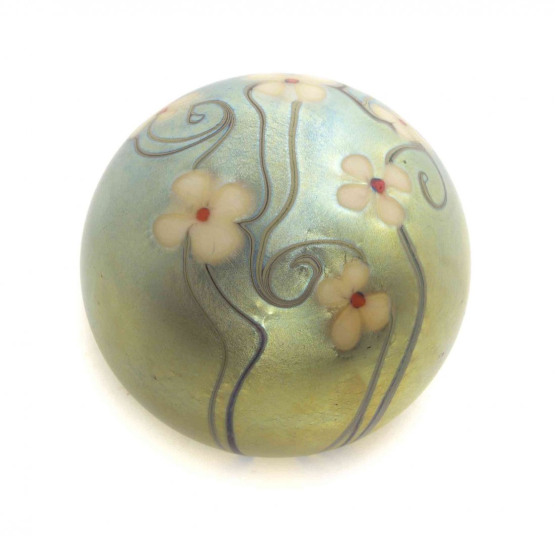A Studio Glass Iridescent Paperweight, Orient and: A Studio Glass Iridescent Paperweight, Orient and Flume, with stylized foliate decoration, dated 1976. Diameter 3 inches.