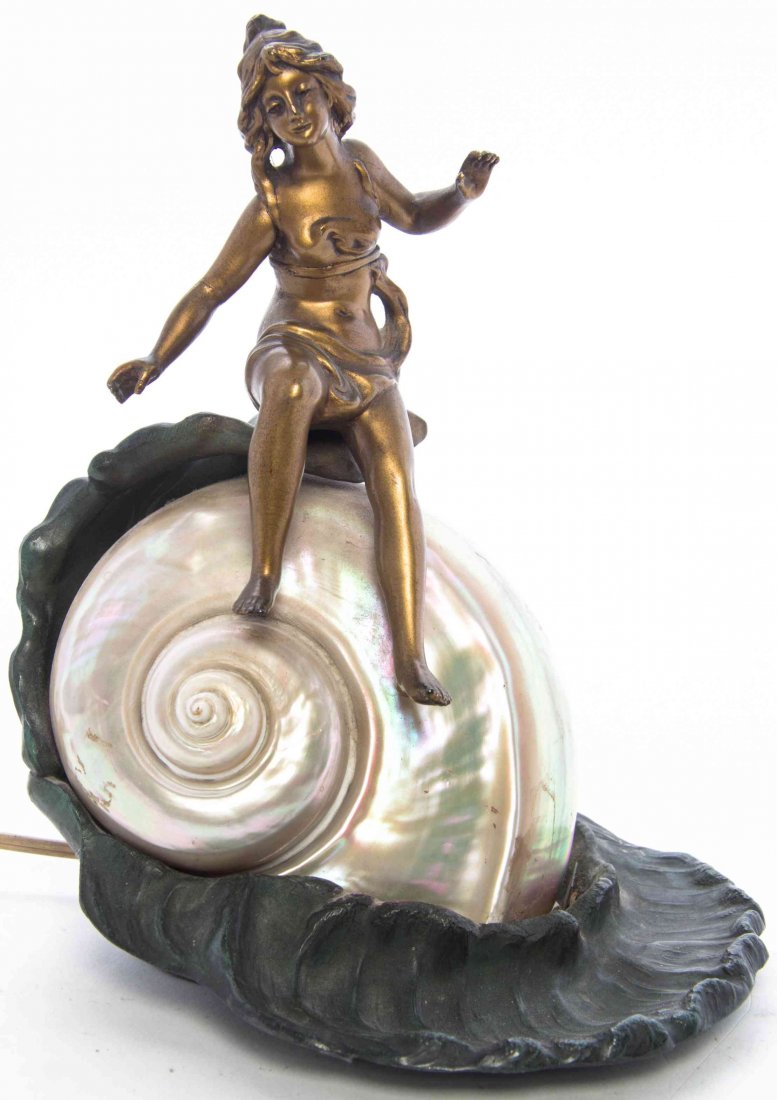 An Art Nouveau Cast Metal Nautilus Figural Lamp, Height: An Art Nouveau Cast Metal Nautilus Figural Lamp, in the form of a shell surmounted with a young girl. Height 8 1/4 inches. Property from the Collection of Thomas and Elaine Rath, Hinsdale, Illinois