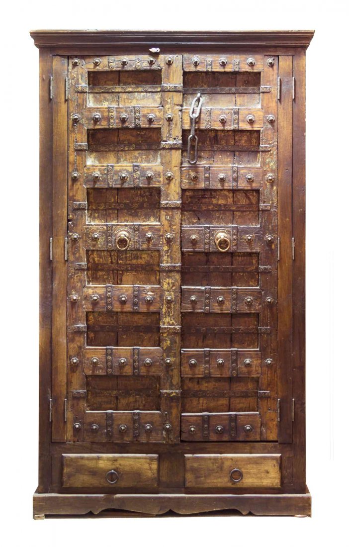 A Continental Carved Wood Wardrobe, Height 87 x width: A Continental Carved Wood Wardrobe, having iron rosette mounts and chain, with a molded cornice and double drawer bracket base. Height 87 x width 51 x depth 29 inches.