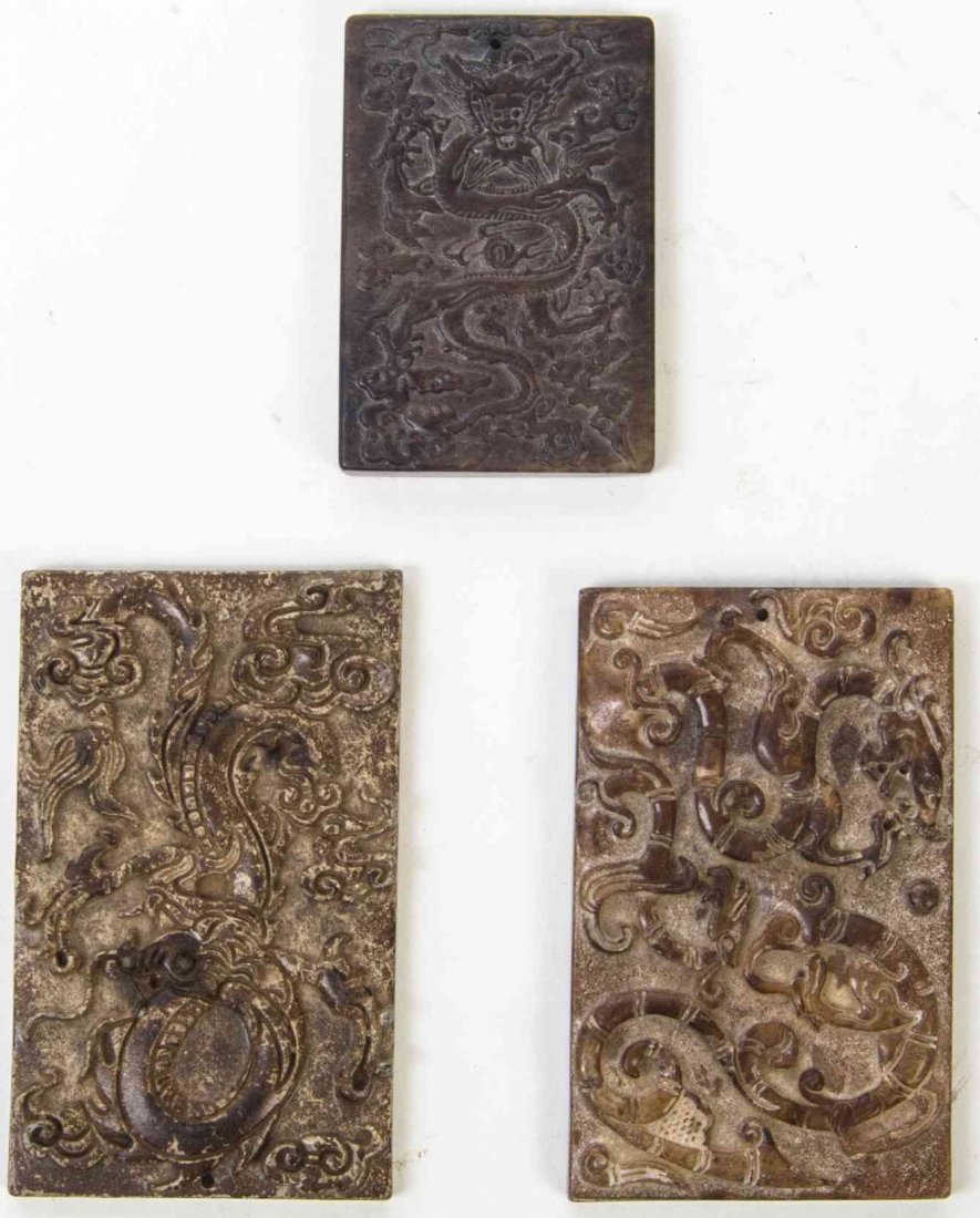 Three Carved Stone Plaques, Height of first 3 1/2: Three Carved Stone Plaques, the first a Han style russet soapstone example depicting sinuous chilong in profile, the second a jade plaque carved in low relief with a forward-facing dragon, the reverse