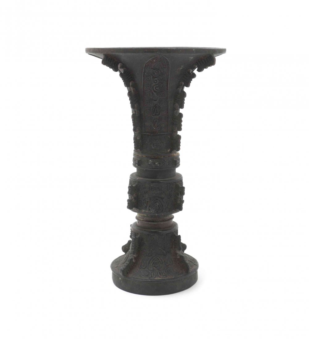 An Archaistic Bronze Gu Vase, Height 8 1/4 inches.: An Archaistic Bronze Gu Vase, late Ming Dynasty, having relief taotie and archaistic decoration, with raised flanges along the neck, center and flared base. Height 8 1/4 inches.