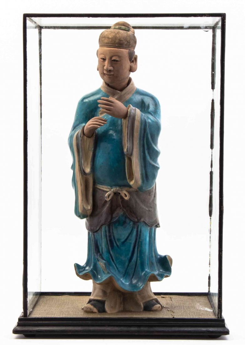 A Chinese Glazed Pottery Figure, Height of figure 22: A Chinese Glazed Pottery Figure, depicting an official in turquoise glazed robes, with unglazed head and hands, set in a custom made display case. Height of figure 22 inches.