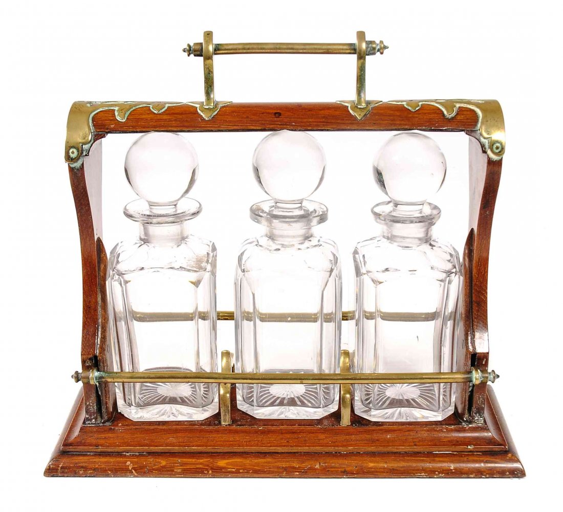 An English Mahogany and Brass Mounted Tantalus, Height: An English Mahogany and Brass Mounted Tantalus, fitted with three lead glass decanters with ball form stoppers. Height 12 1/2 x width 13 3/4 x depth 5 1/4 inches.