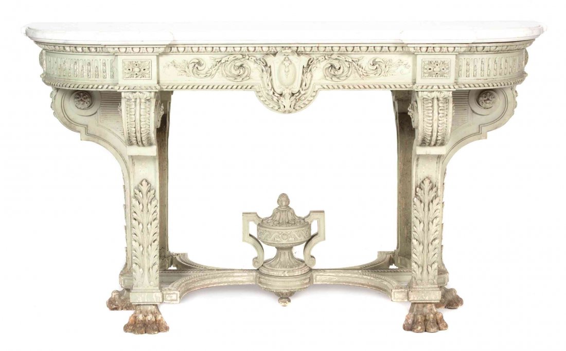 A Rococo Style Painted Carved Wood and Marble Top: A Rococo Style Painted Carved Wood and Marble Top Console Table, having a rectangular top with rounded corners over an ornately carved frieze centered with a shield flanked by scrolling foliate design
