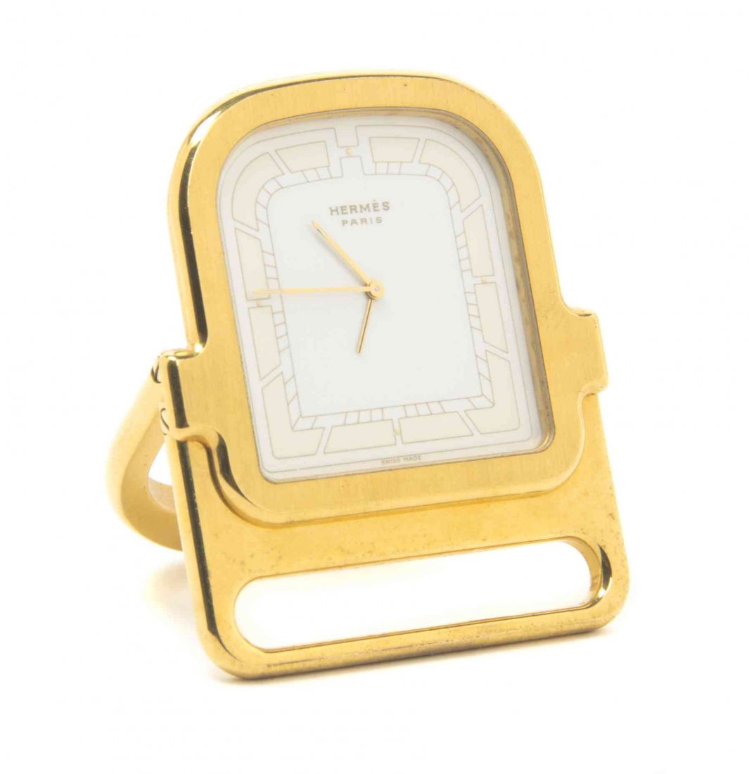 A French Gilt-Metal Pendulette Fontainebleau Travel: A French Gilt-Metal Pendulette Fontainebleau Travel Clock, Hermes, Paris, Circa 1987 shaped rectangular with arched frame, dial without numerals and a hinged horseshoe-form support, with original fitt