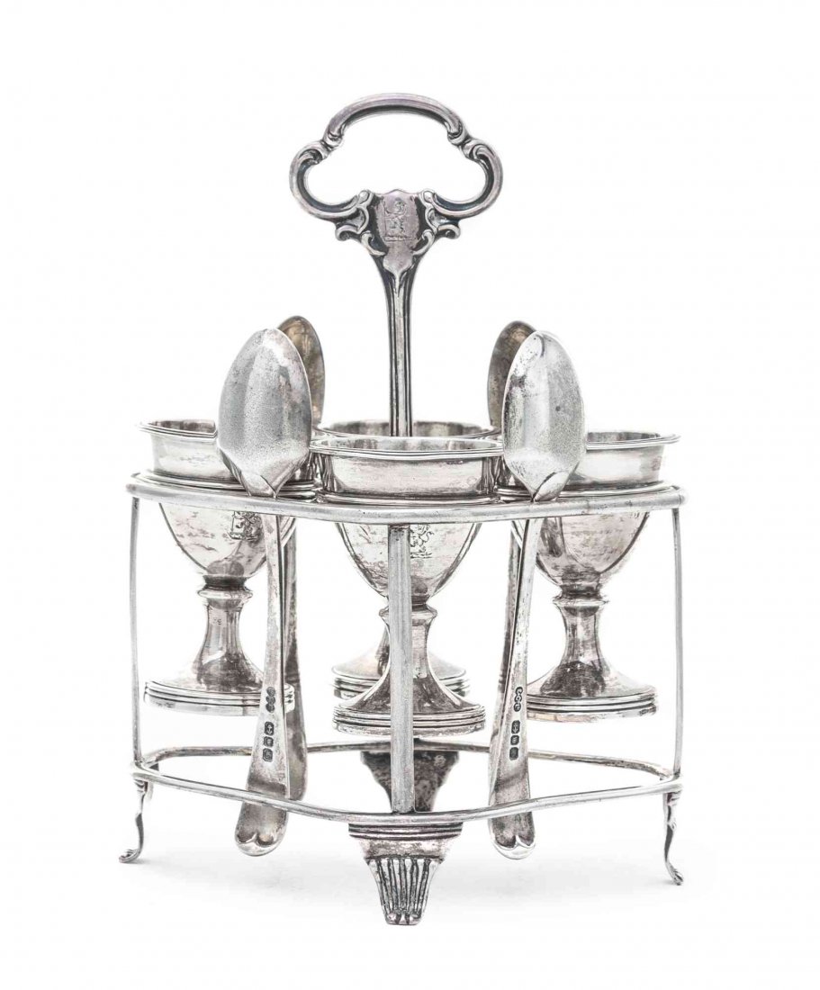 A Victorian Egg Cup Holder, John Harris IV, London,: A Victorian Egg Cup Holder John Harris IV, London, 1847 the stand of shaped oval form raised on four reeded feet, central handle engraved with lion crest, with 4 detachable cups; together with 4 spoon