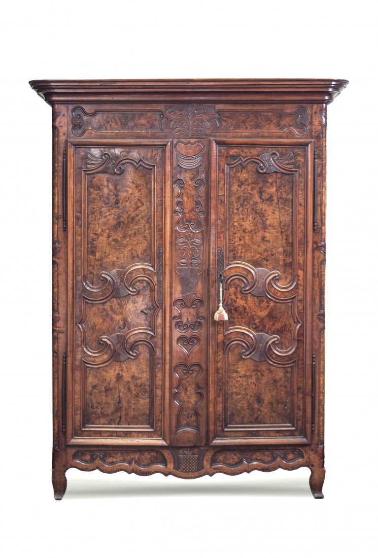A French Provincial Walnut Armoire, Height 84 x width: A French Provincial Walnut Armoire, having a molded cornice over two paneled doors carved in relief with flowering vines, opening to a shelved interior, raised on cabriole legs joined by a floral carv