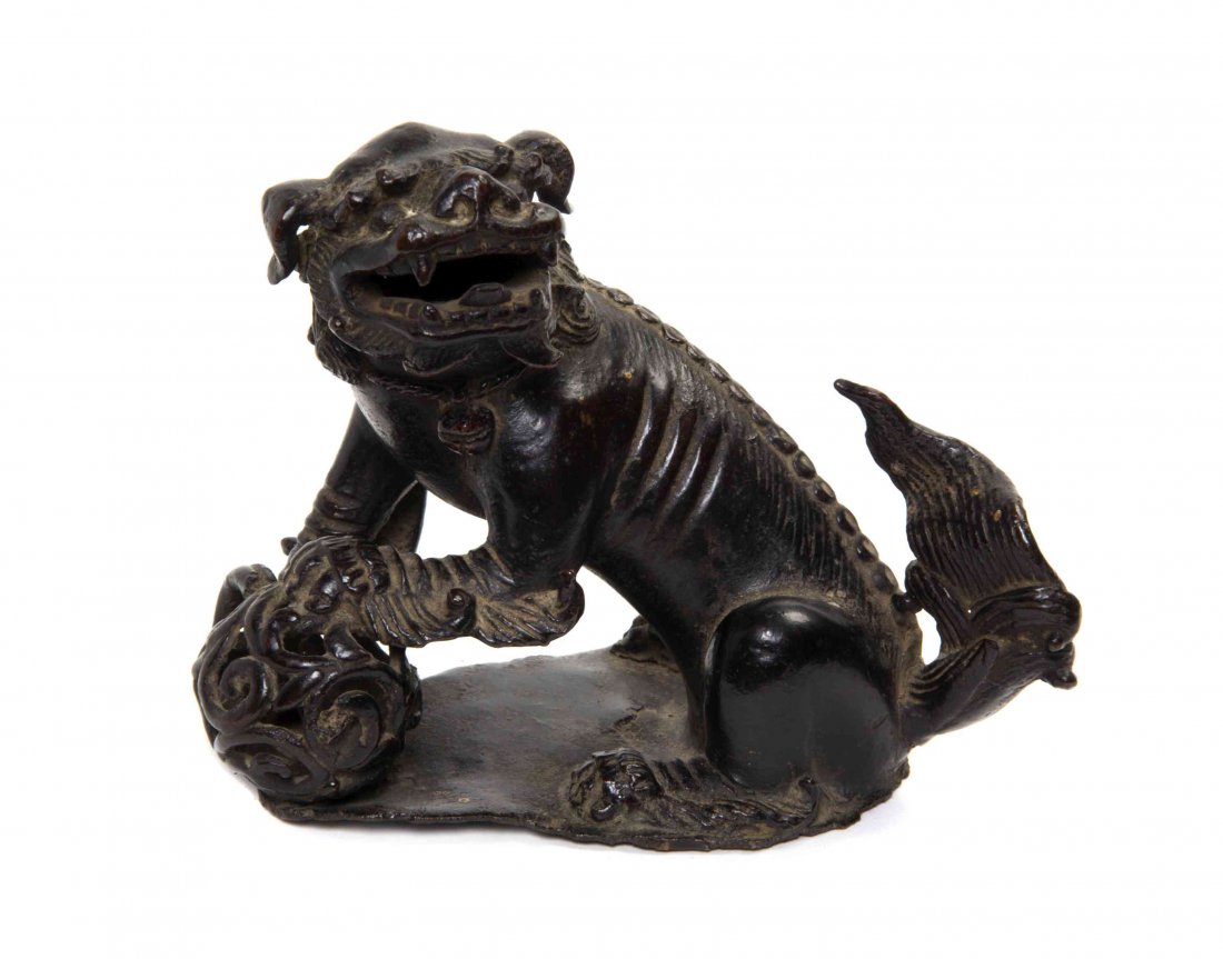 A Chinese Cast Metal Temple Lion, Width 5 1/4 inches.: A Chinese Cast Metal Temple Lion, depicted with one front paw raised on a ball. Width 5 1/4 inches.