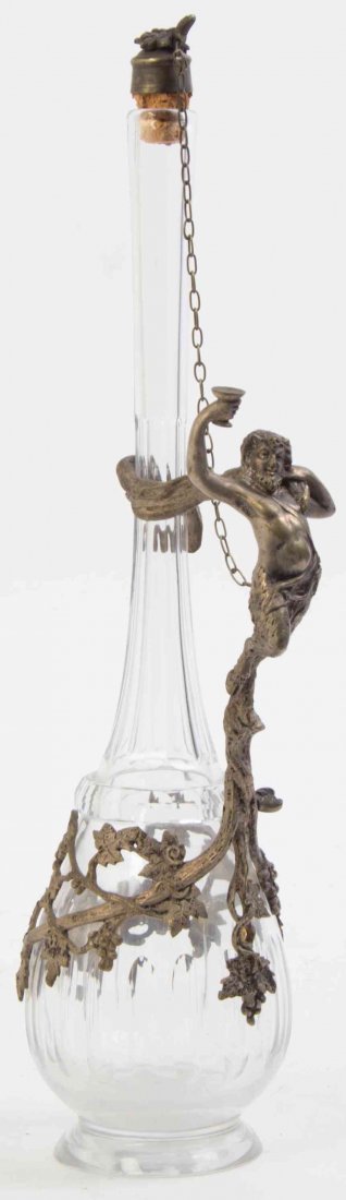 A Continental Silvered Metal-Mounted Cut Glass: A Continental Silvered Metal-Mounted Cut Glass Decanter Possibly Italian, Early 20th Century the glass of baluster form with elongated neck, mounted with metal grapevine centered by a rococo reserve a