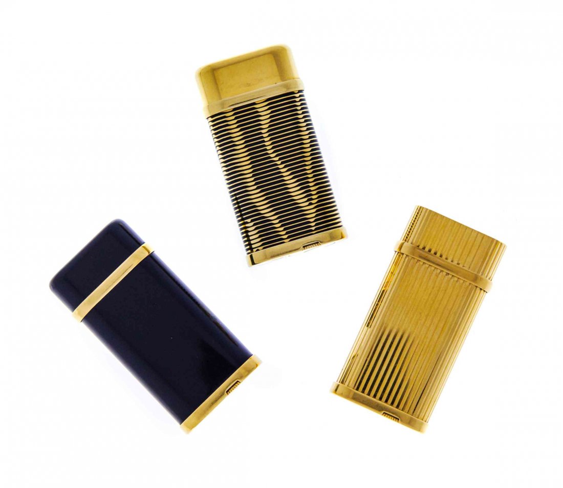 Three Gold-Plate Lighters, Cartier, Circa 1970,: Three Gold-Plate Lighters Cartier, Circa 1970 comprising one with vertically ribbed body and cover, another with horizontal ribs inset with black lacquer, and a third with black lacquer sides and gold