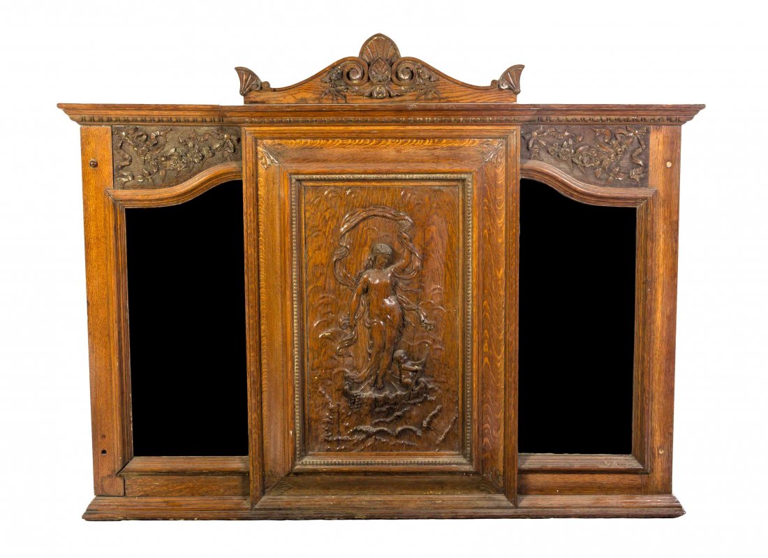 An American Art Nouveau Oak Over Mantel Mirror Height: An American Art Nouveau Oak Over Mantel Mirror having a palmette carved peak crest above a vertical panel relief, carved with a female figure and putto flanked by shaped beveled plates. Height 46 1/2 