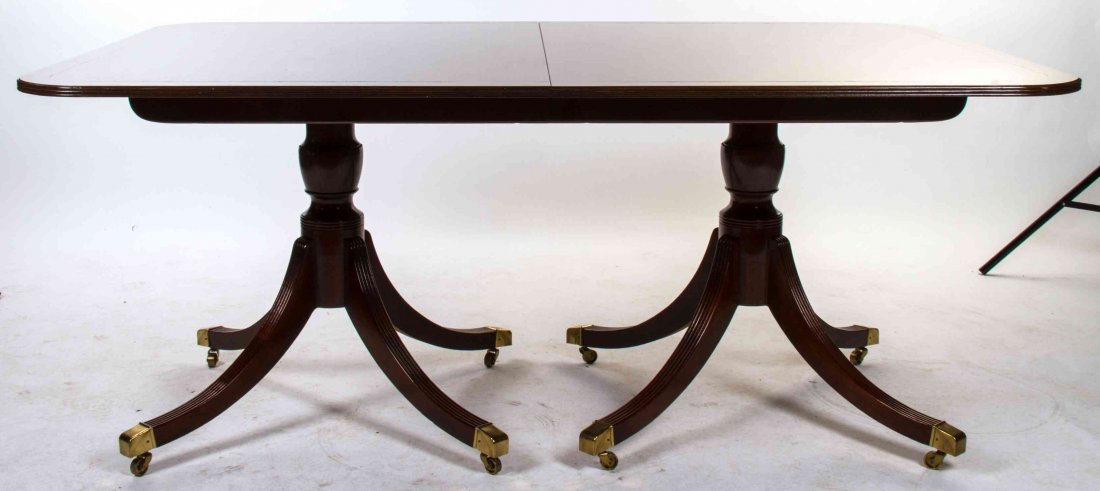A Georgian Style Mahogany Dining Table Height 20 1/4 x: A Georgian Style Mahogany Dining Table BAKER having a rectangular banded top with rounded corners and a reeded edge raised on twin pedestals ending in brass caps and casters. Height 20 1/4 x width 67