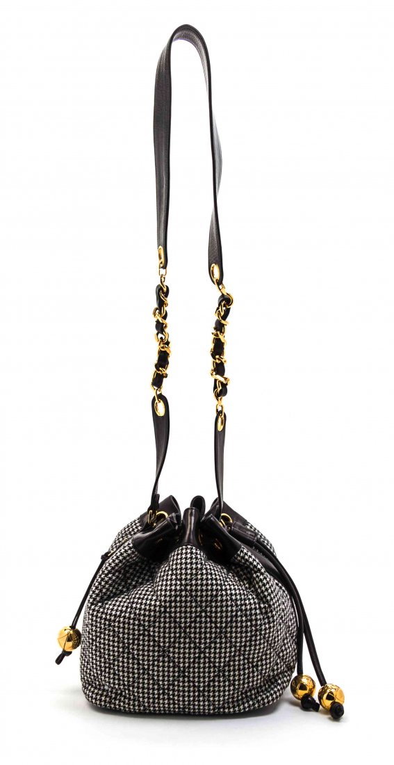 A Chanel Black and White Houndstooth Wool and Black: A Chanel Black and White Houndstooth Wool and Black Leather Trim Bucket Bag, goldtone hardware, leather and interwoven leather and chain link shoulder strap, exterior zippered pocket with decorative p