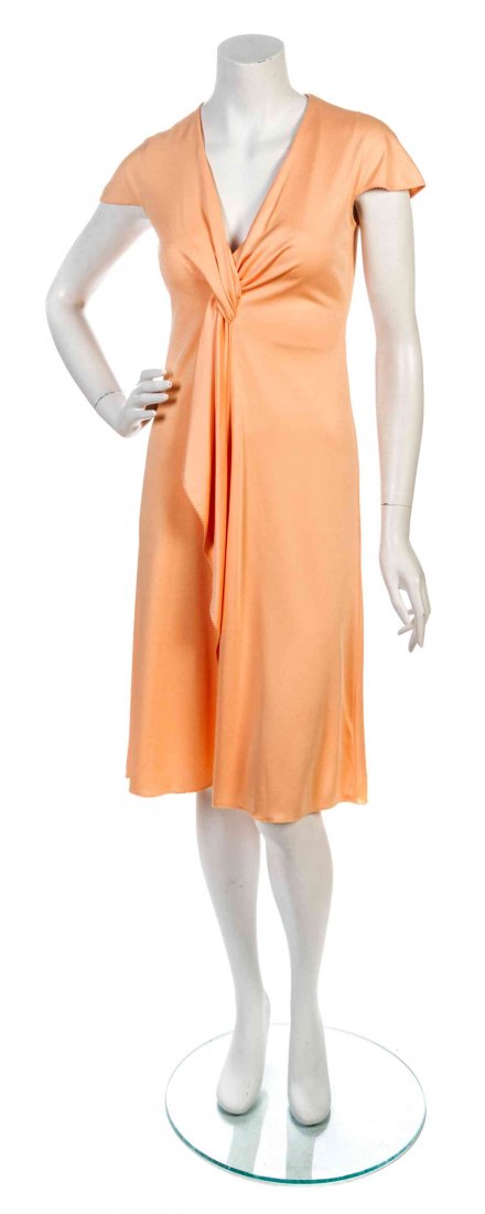 A Stephen Burrows Apricot Jersey Knit Dress,: A Stephen Burrows Apricot Jersey Knit Dress, 1970's, cap sleeve, with a deep v-neck and a knot draped front with signature lettuce edge hem. Labeled: Stephen Burrows. Property from a Private Collector