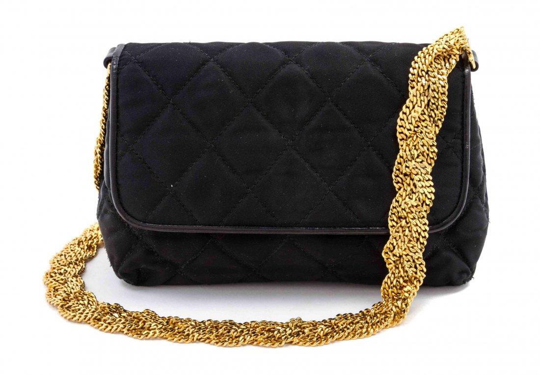 A Chanel Black Satin Quilted Bag, 7 1/2 x 4 1/2 x 2 1/2: A Chanel Black Satin Quilted Bag, circa 1987, braided goldtone chain shoulder strap, quilted interlocking 'C' logo on the bottom, foldover flap with button closure, interior zippered pocket, red leath