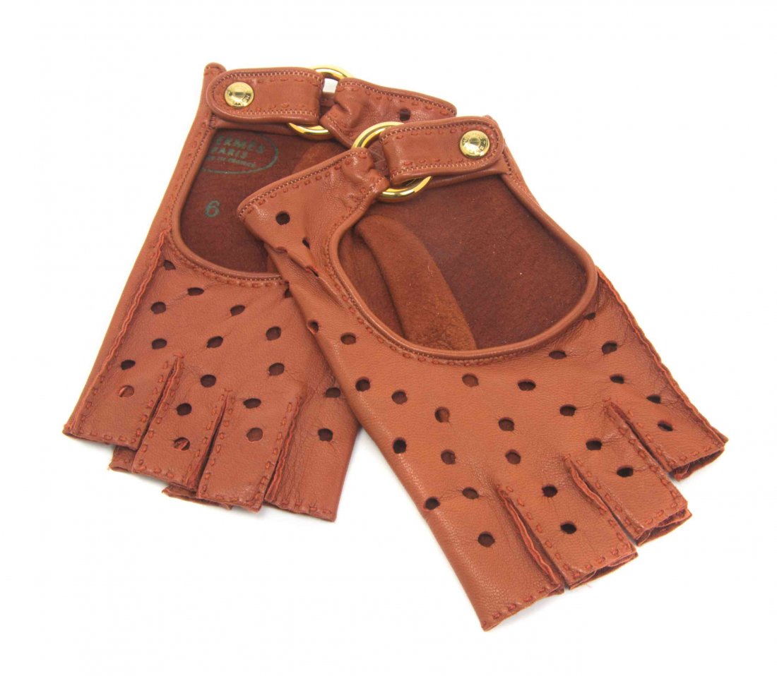 A Pair of Hermes Sienna Perforated Leather Conduit 2: A Pair of Hermes Sienna Perforated Leather Conduit 2 Driving Gloves, adjustable goldtone ring and Clou de Selle buttons. Labeled: Hermes. Size 6. Property from the Collection of a Lady, New York and L