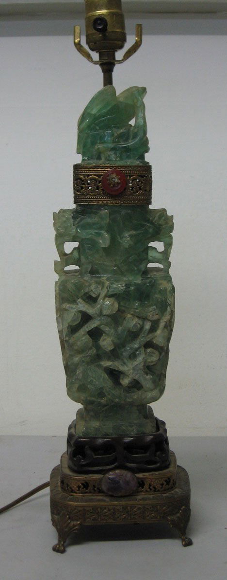 Carved jade sculpture mounted as a lamp, , With p: Carved jade sculpture mounted as a lamp With pierced brass bands and applied stoned. H: 19 in.