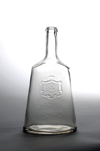 Glass Bottle from Jacob Haberfeld Factory – Oswiecim: Glass bottle, made by Jacob Haberfeld liquor factory in Oswiecim. Oswiecim, [pre WW II]. Factory's emblem in the center and the inscription: "Jacob Haberfeld Oswiecim". The factory was established in 
