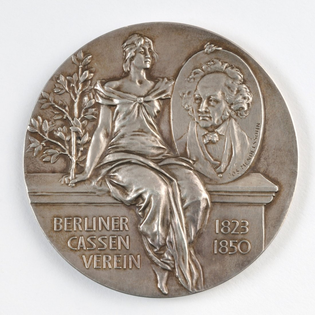 Silver Medal â€“ Bank in Berlin â€“ Joseph Mendelssohn: Silver medal - Berliner Kassen-Vereins Bank. [Berlin, 1850]. Obverse: A woman holding a plate with the portrait of the Jewish banker Joseph Mendelssohn and an inscription "Berliner Cassen Verein 1823 