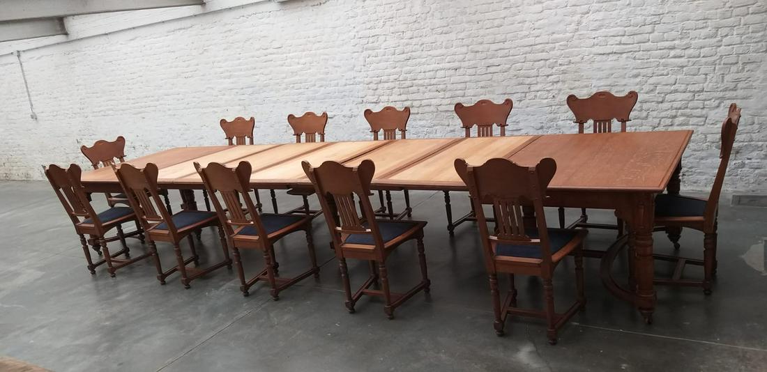 GUSTAVE SERRURIER-BOVY (1858-1910) Table et douze: GUSTAVE SERRURIER-BOVY (1858-1910) Table et douze chaises en chêne, cinq rallonges. Table sur sept pieds reposant sur des roulettes en laiton, à système à rallonge pour douze perso