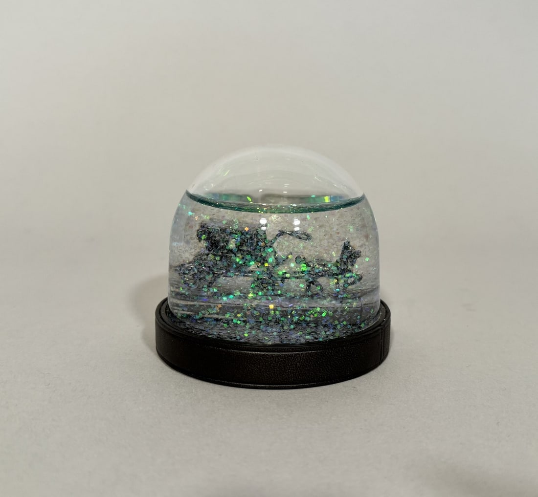 GUERLAIN. « La Petite Robe Noire ».2015.: GUERLAIN. « La Petite Robe Noire ».2015. Boule à neige représentant à l'intérieur la Tour Eiffel et intitulée "La Petite Robe Noire ». Hauteur : 8,5 cm. (Trace de brûlure sur le socle).