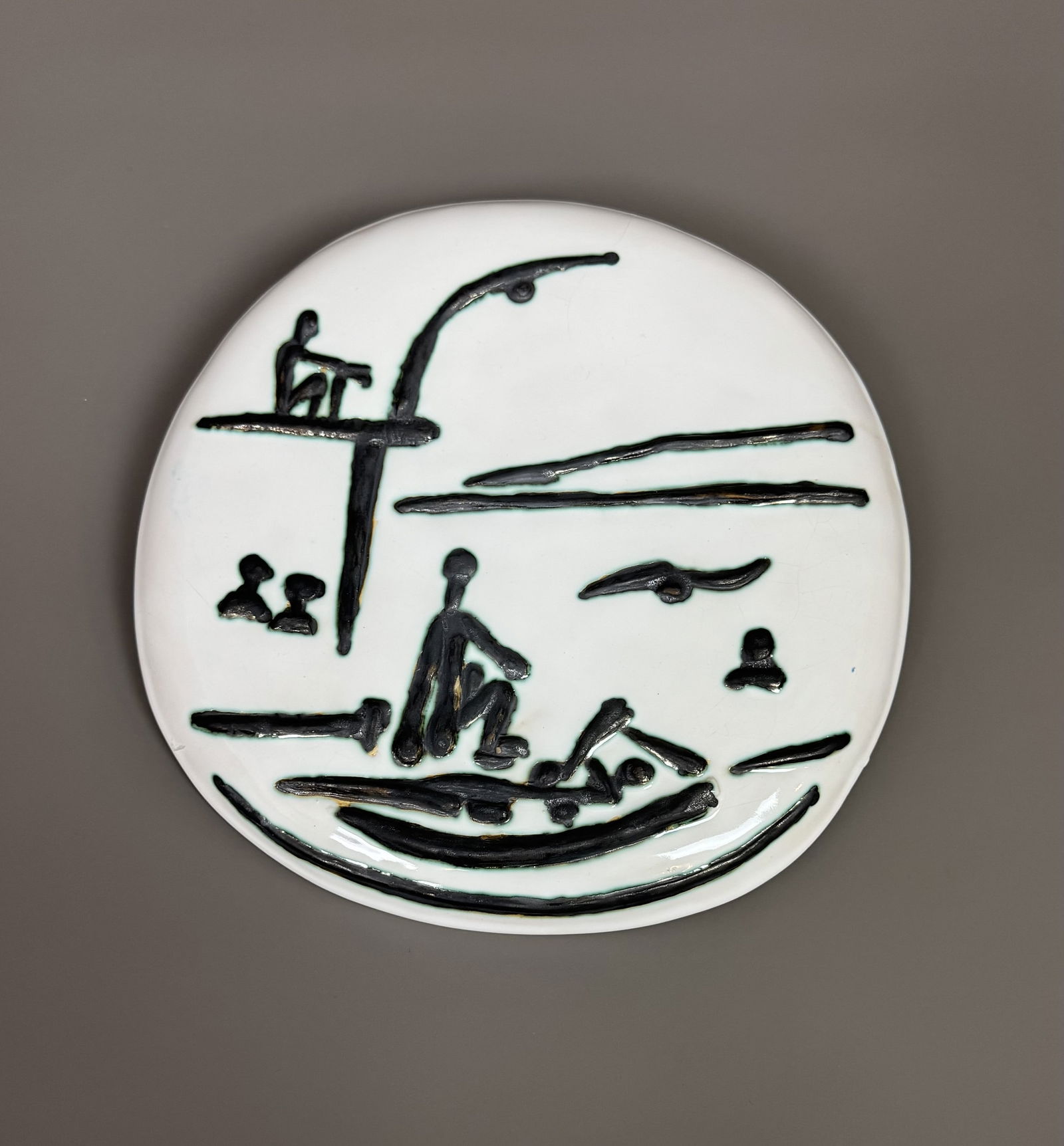 Pablo PICASSO (1881-1973) « Scène de plage (fond blanc) ». 1956.: Pablo PICASSO (1881-1973) « Scène de plage (fond blanc) ». 1956. Plaque murale convexe. Terre de faïence blanche, gravure soulignée de paraffine oxydée, bain de couverte,