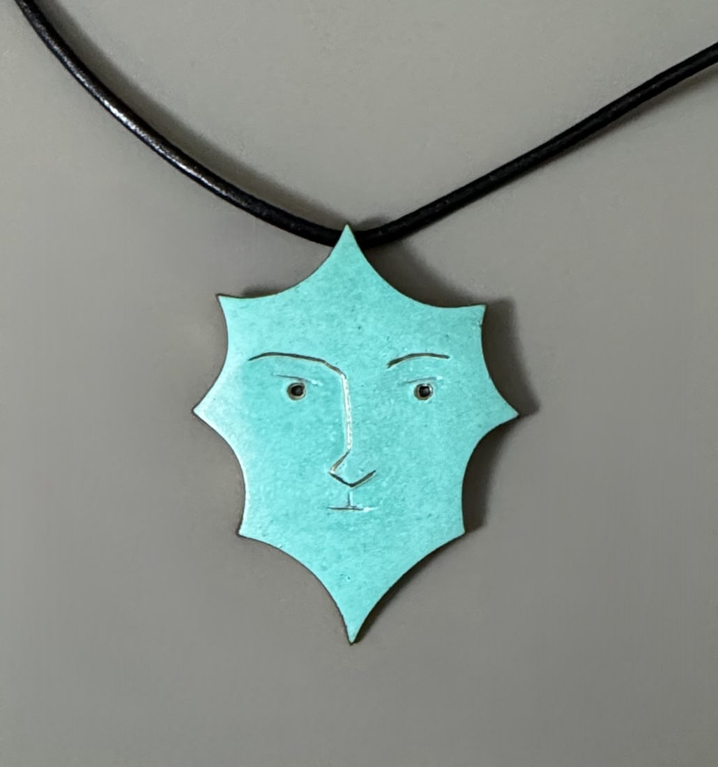 Jean COCTEAU (1889-1963) « Octogone vert ».: Jean COCTEAU (1889-1963) « Octogone vert ». Pendentif en bronze poli et patiné céladon, émail noir dans les yeux et cordon en cuir roulé. D’après un dessin de