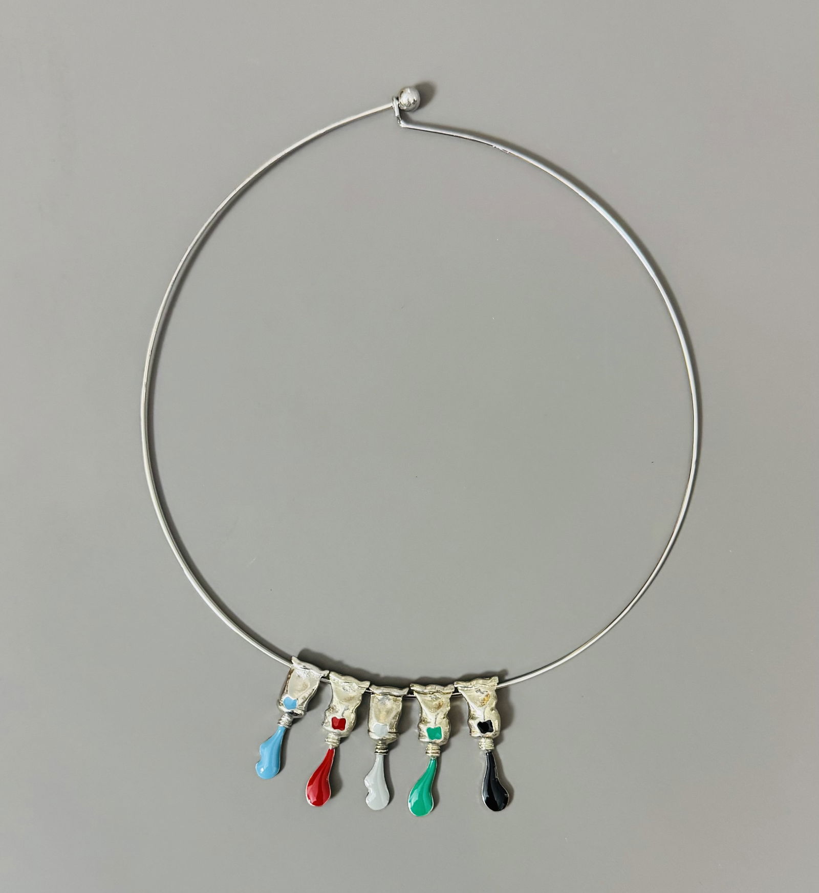 ARMAN FERNANDEZ (1928-2005) « Coulée de Tubes », 2001.: ARMAN FERNANDEZ (1928-2005) « Coulée de Tubes », 2001. Collier composé de cinq pendentifs en forme de tubes de peinture, bleu, rouge, gris, vert et noir. Signé « Arman &#