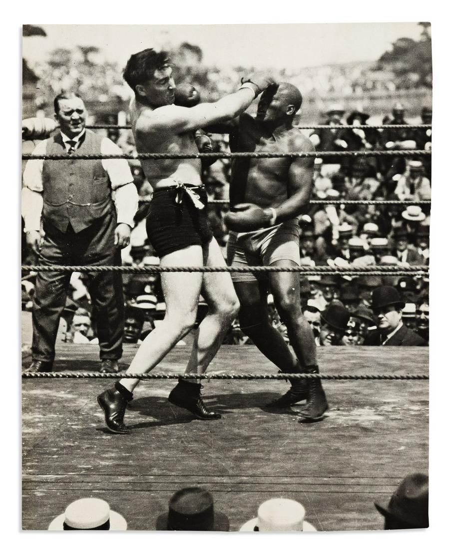 (SPORTS--BOXING.) Press photograph of Jack Johnson landing a punch against Jess Willard in 1915.: (SPORTS--BOXING.) Press photograph of Jack Johnson landing a punch against Jess Willard in 1915. Photograph, 7½ x 6 inches, with International News Photos inked stamp and pencil captions on verso