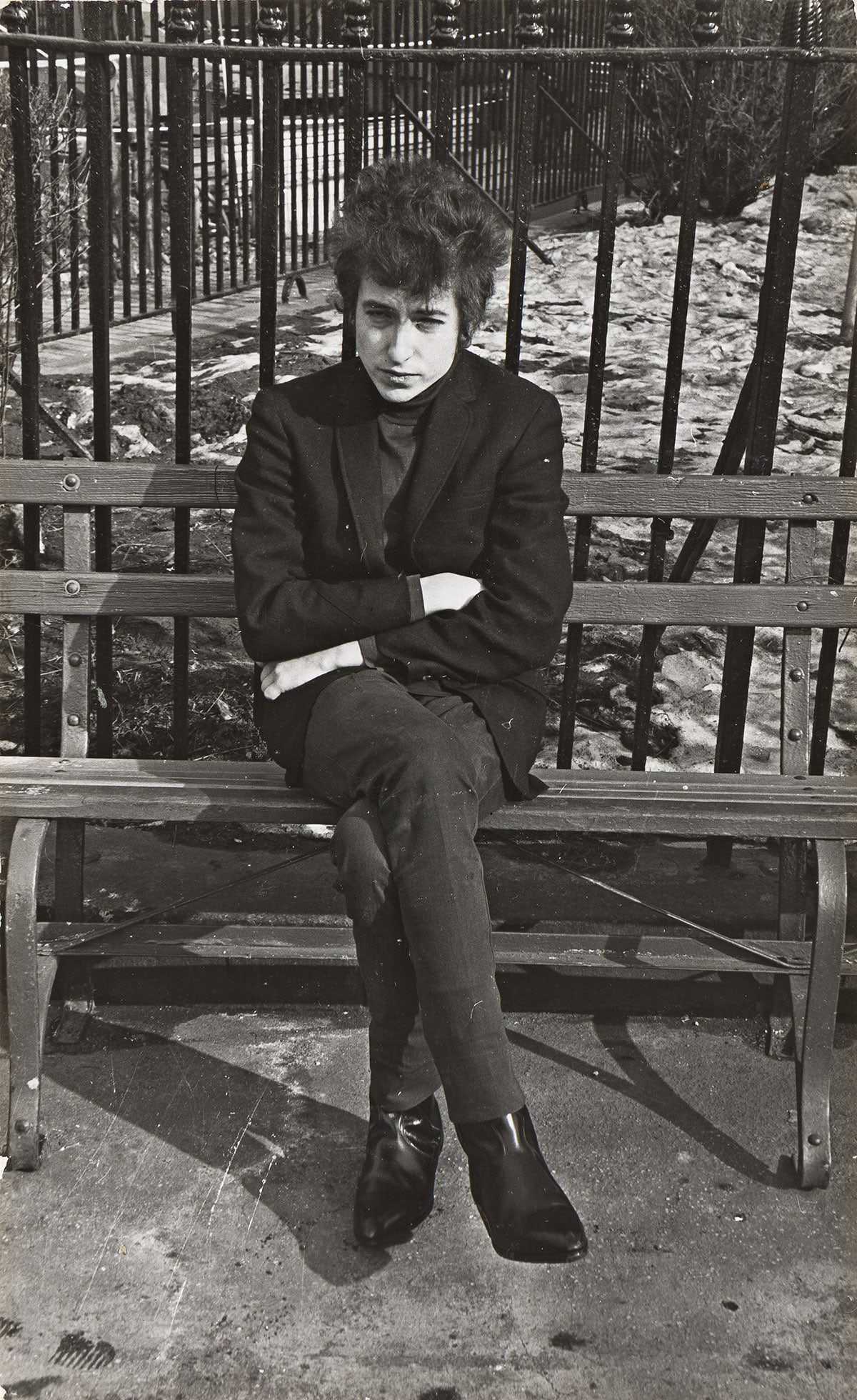 FRED W. MCDARRAH (1926-2007) An unpublished photograph of Bob Dylan on bench in Sheridan Square.: FRED W. MCDARRAH (1926-2007) An unpublished photograph of Bob Dylan on bench in Sheridan Square. 1965. Silver print, the image measuring 197x121 mm; 7¾x4¾ inches, with McDarrah's signature i