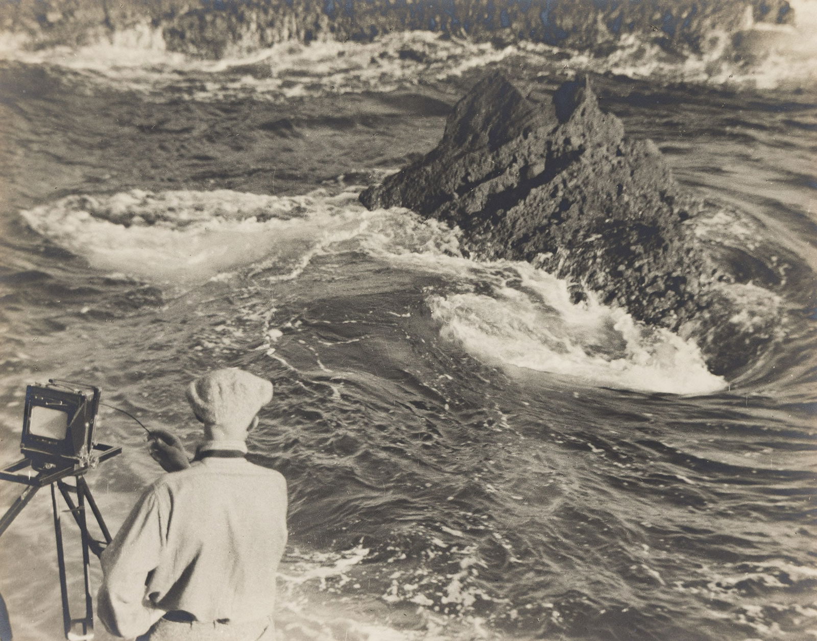 Dain L. Tasker. Photographing the waves (possibly Will Connell). Circa 1920.: Dain L. Tasker1872-1964Photographing the waves (possibly Will Connell). Circa 1920.Silver printWith Tasker's signature in pencil on mount recto.The image 10 1/8 x 13 in. (25.7 x 33 cm.), the mount 18