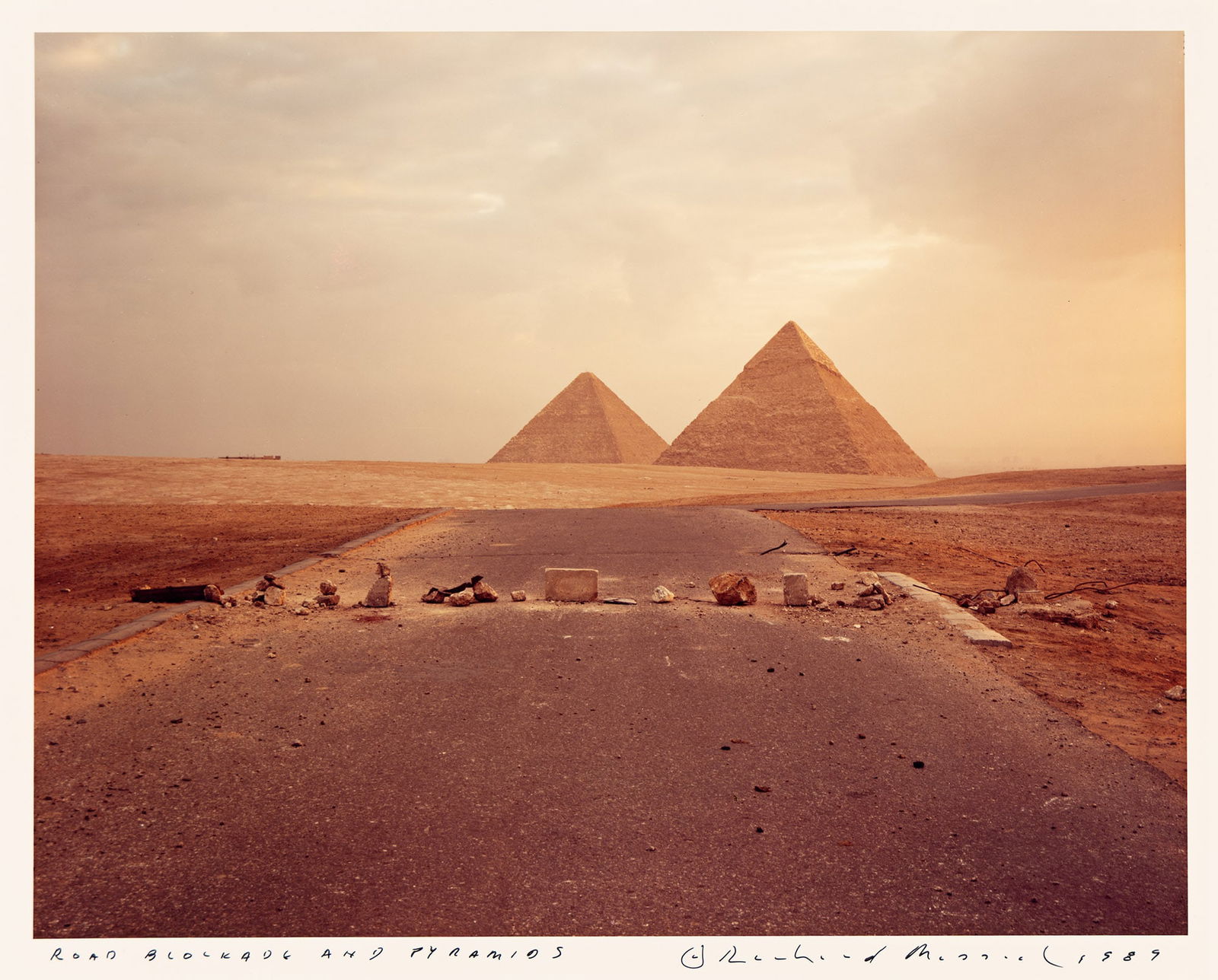 Richard Misrach. Road Blockade and Pyramids. 1989.: Richard Misrach1949-Road Blockade and Pyramids. 1989.Chromogenic printWith Misrach's signature, title, and date in ink on recto.The image 9 1/4 x 11 7/8 in. (23.5 x 30.2 cm.), the sheet 11 x 14 in. (2
