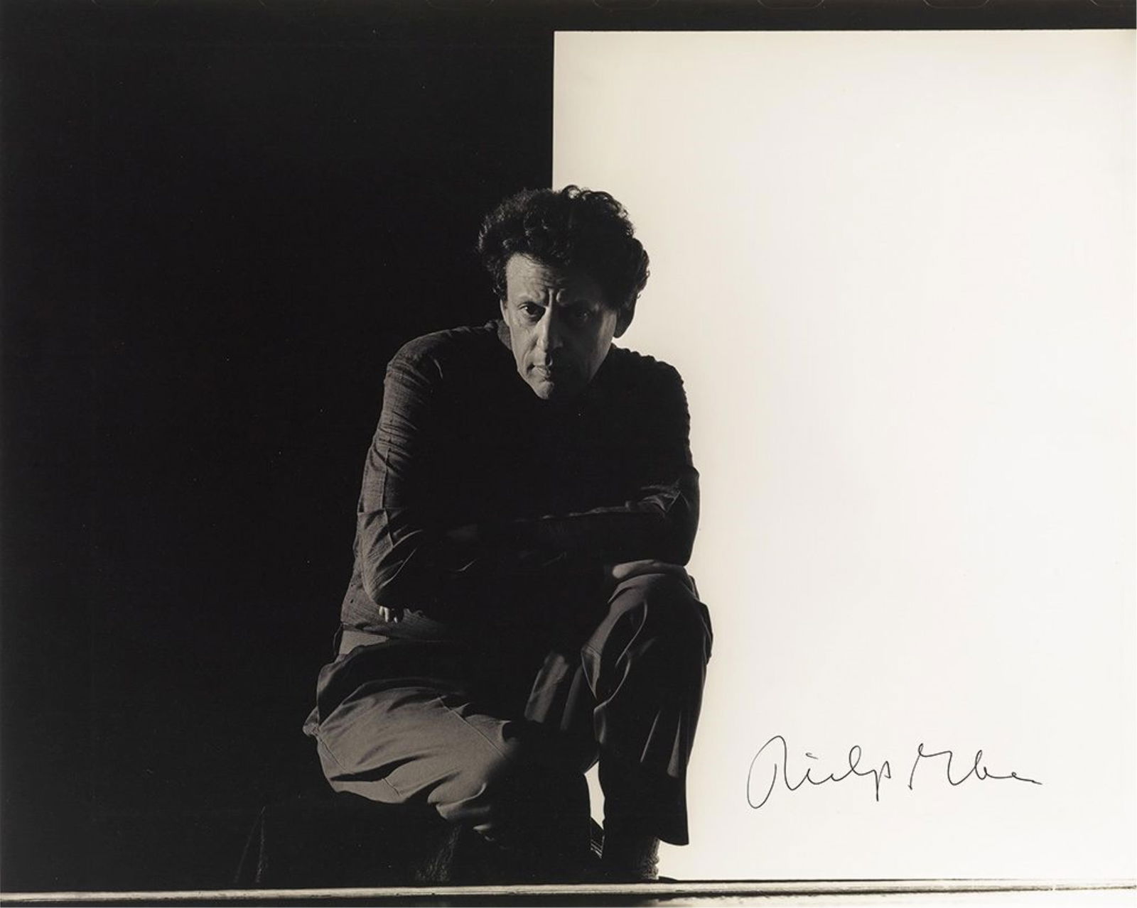 Philip Glass. Large Photograph Signed: Master of minimalism in split tones Philip Glass Large Photograph Signed, half-length portrait by Tom Caravaglia showing him squatting before a duotone backdrop and looking into camera. Signed at lowe