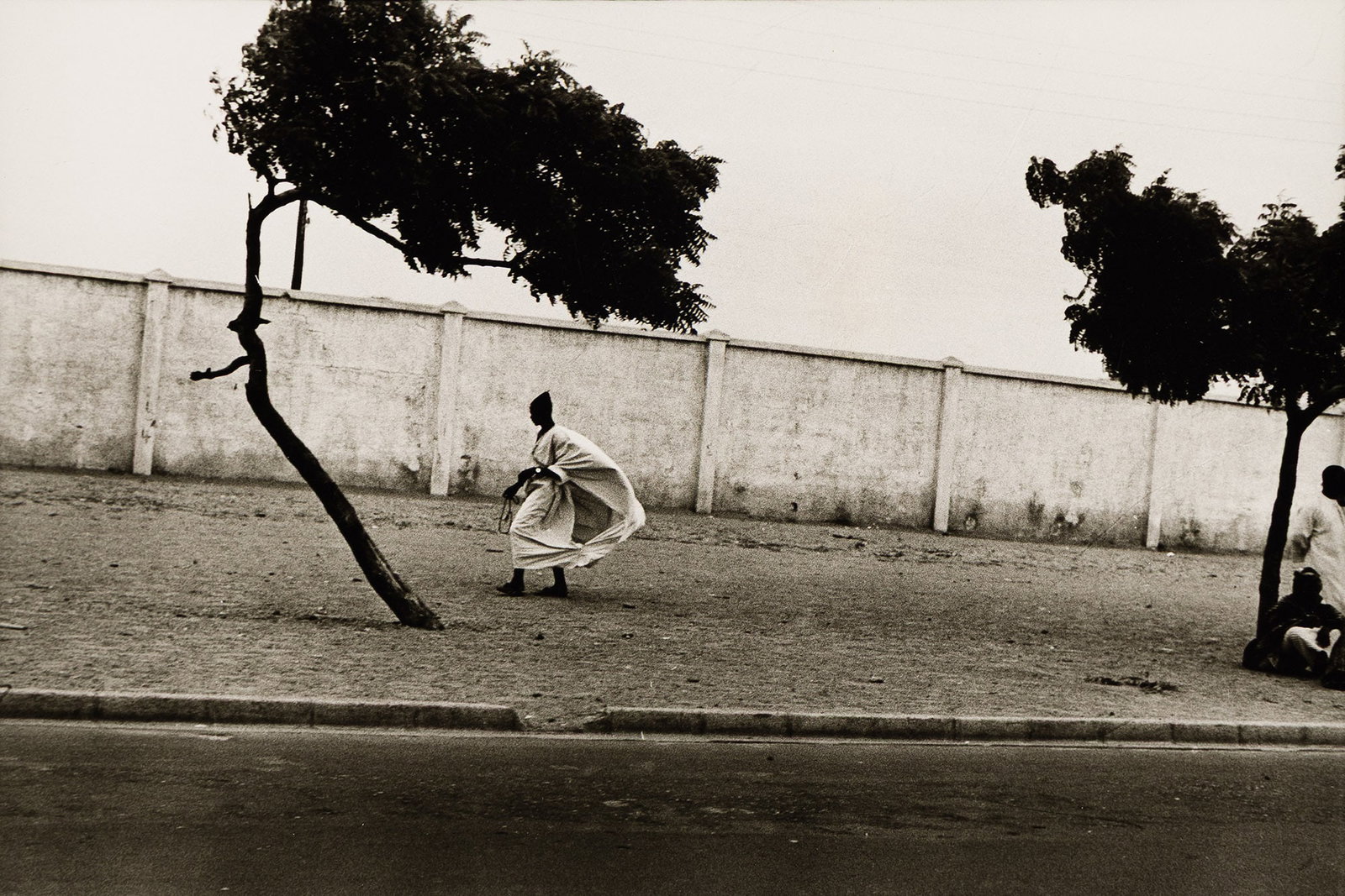 Ming Smith (b. 1950), Dakar Roadside with Figures (Senegal), 1972.: Ming Smith (b. 1950) Dakar Roadside with Figures (Senegal). Silver print, 1972. Printed by Anthony Barboza. Inscribed by Anthony Barboza in pencil, verso. Image: 4 3/4 x 7 in. (12.1 x 17.8 cm.), Sheet