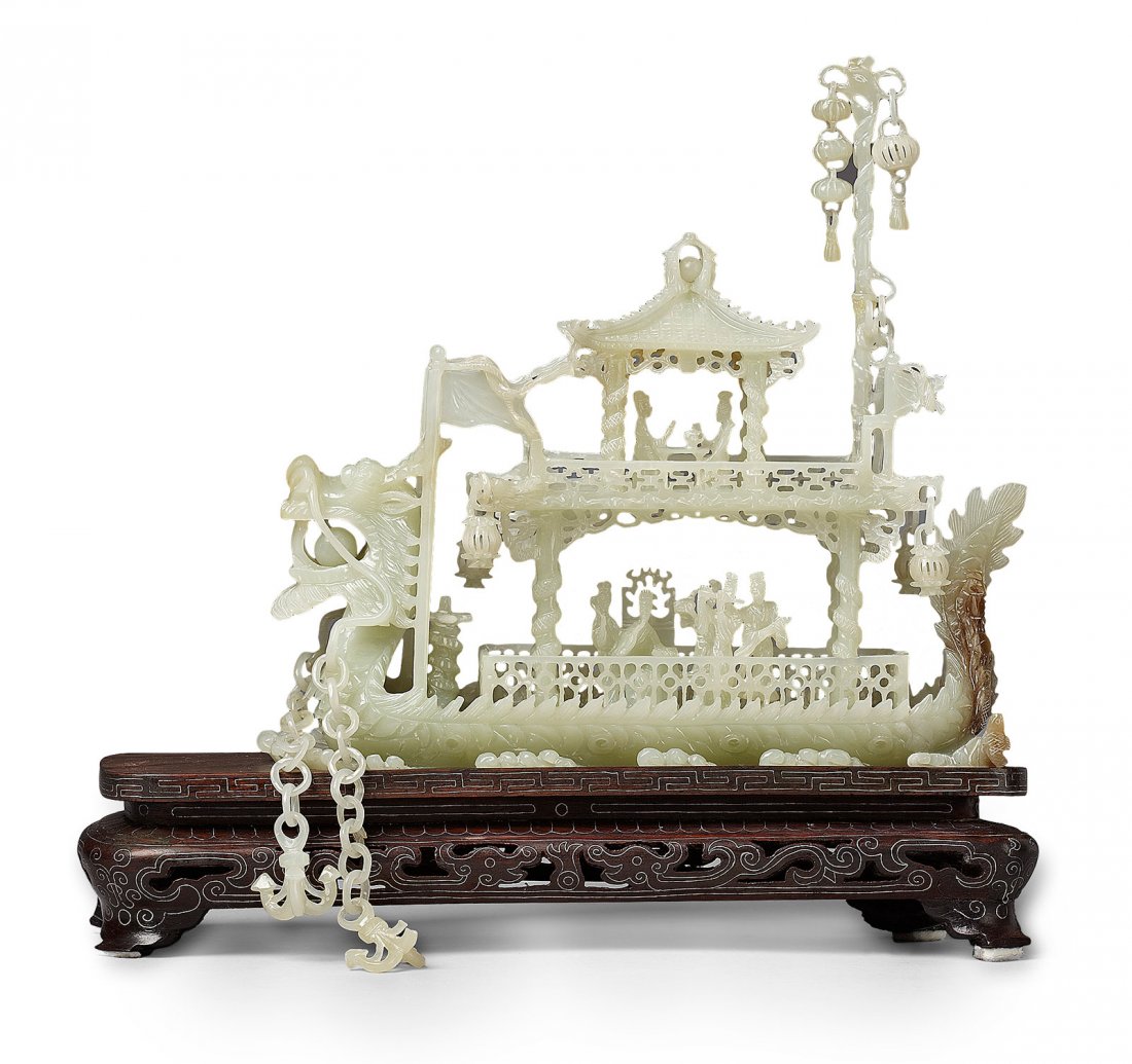 Carved jade model of a dragon boat, China, 20th c.: Carved jade model of a dragon boat, China, 20th c. on a wooden stand. Height: 19 cm, Length: 20.5 cm Intricately carved and pierced in the shape of a dragon. The large head of the dragon, holding a pe