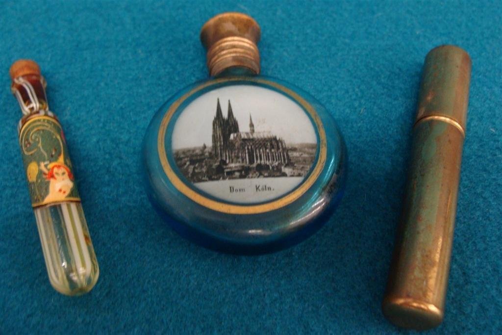 Two Antique perfume Bottles: One is Tube Shaped with: Two Antique perfume Bottles: One is Tube Shaped with Metal Holder; The Other is a Blue Glass with a Painting of Dom Koln. Auction Estimate $100-200.