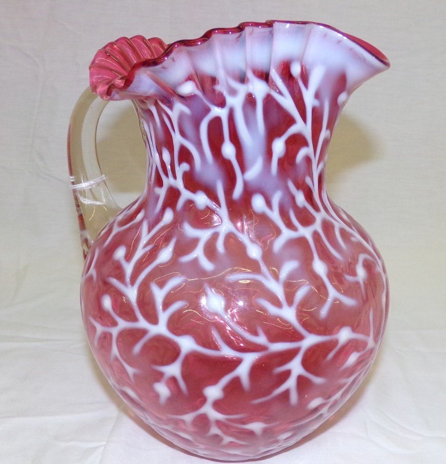 Cranberry Opalescent Art Glass Pitcher with Ruffled Top: Cranberry Opalescent Art Glass Pitcher with Ruffled Top Applied Clear Handle & Seaweed Design. Auction Estimate $100- 200.